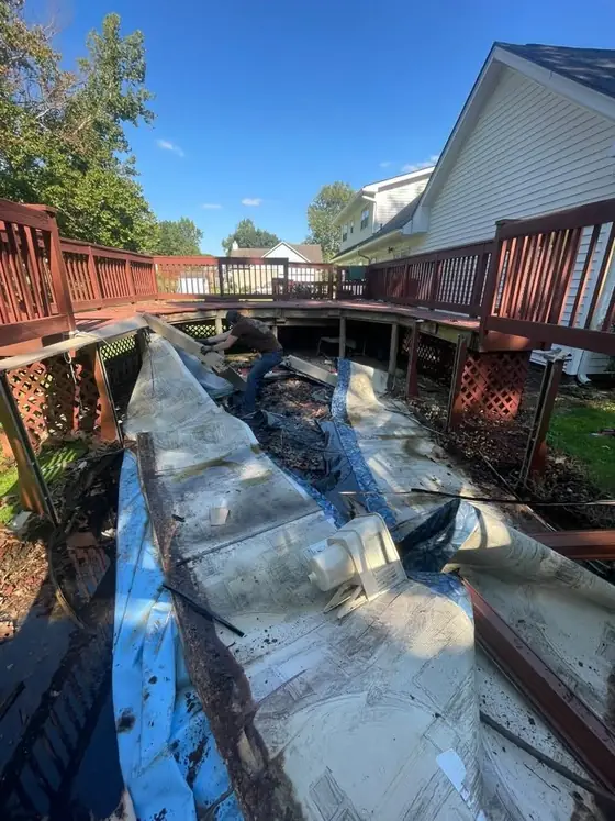 AdVance Junk Removal cutting apart the pool liner and wall panels on the deck during teardown