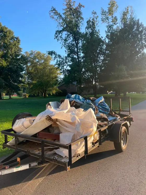 AdVance Junk Removal trailer loaded with pool liner, decking and debris on a Kentucky street at golden hour